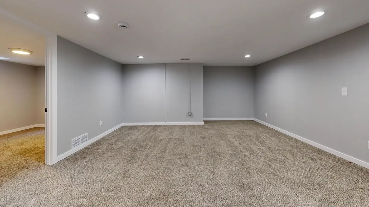 An open, finished lower-level room with neutral walls