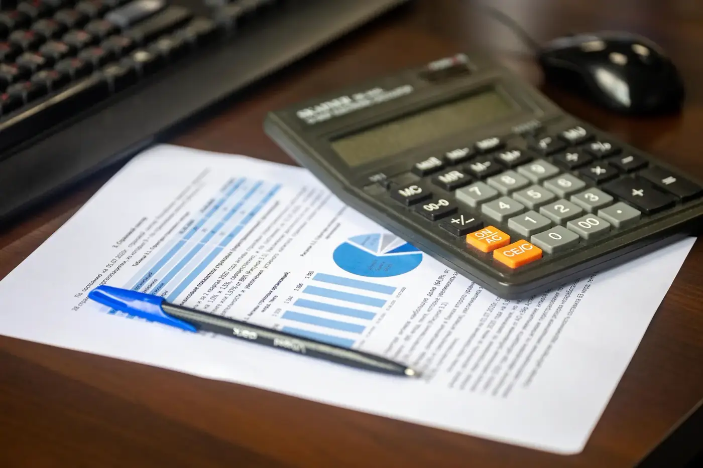 A calculator, pen and financial report laid out on a desk